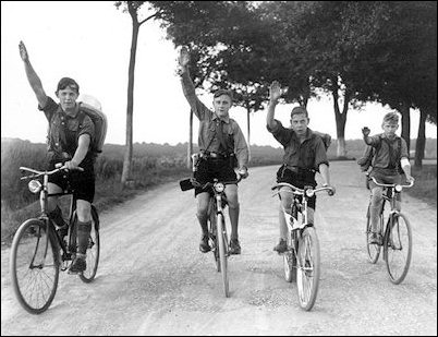 Four Hitler Youths peddle toward Berlin while displaying the Nazi salute during a bike tour in 1932. 